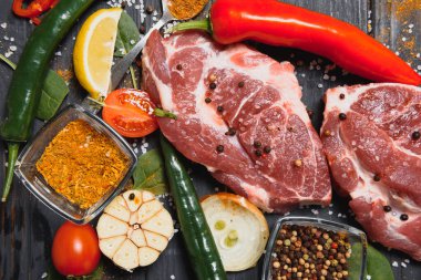 Mutfak masasındaki ahşap kesme tahtasında çiğ domuz eti. Biftek pişirmek için. Kavrulmuş ya da baharatla kızartılmış.