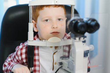 Dürbünlü lambayla oğlanın görme testi. Bir gencin gözünün retinasını yakından kontrol ediyorum. Oftalmoloji Kliniği