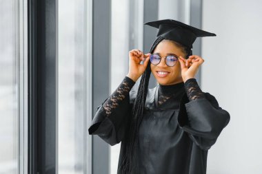 Mezuniyet töreninde diploması olan mutlu Afrikalı Amerikalı kız öğrenci.