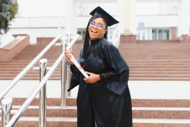 Mezuniyet töreninde diploması olan mutlu Afrikalı Amerikalı kız öğrenci.