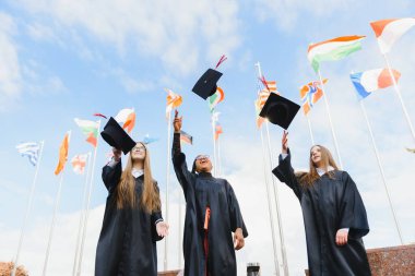 Öğrenciler mezuniyet şapkalarını havaya atıp kutlama yapıyorlar.