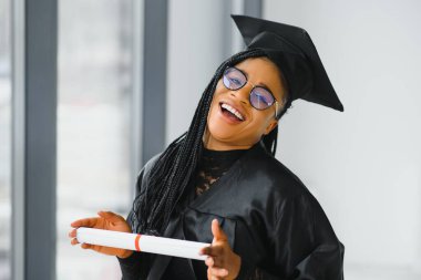 Mezuniyet töreninde diploması olan mutlu Afrikalı Amerikalı kız öğrenci.