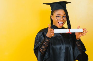 Mezuniyet töreninde diploması olan mutlu Afrikalı Amerikalı kız öğrenci.