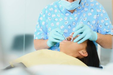 Klinikte tedavi edilmeden önce erkek dişçinin kadın hastaya önlük ayarlaması