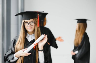 Eğitim teması: Akademik elbiseyle mezun olan kız.