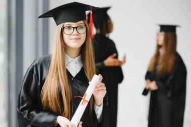 Eğitim teması: Akademik elbiseyle mezun olan kız.