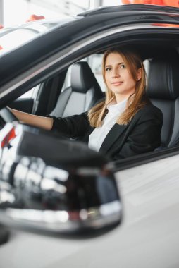 Genç ve güzel bir iş kadını arabasında oturuyor.