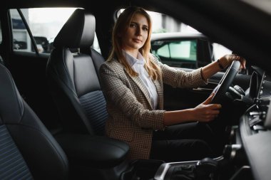 Genç ve güzel bir iş kadını arabasında oturuyor.