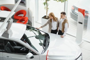 Genç, güzel, mutlu bir çift araba alıyor. Koca, karısı için kuaförden araba alıyor. Araba alışveriş konsepti.