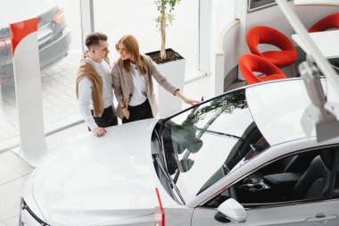 Otomobil galerisinde gülümseyen genç çift.