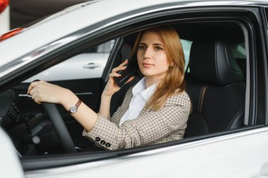 Genç ve güzel bir iş kadını arabasında oturuyor.