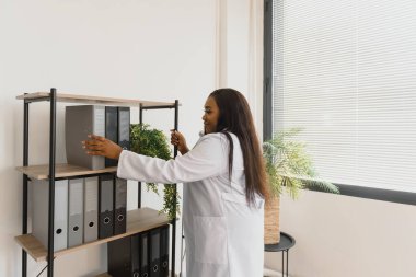 Beyaz önlüklü, steteskoplu güzel Afrikalı Amerikalı kız doktor.