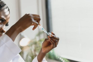 Genç Afro-Amerikalı kadın doktorun elinde şırıngayla hastanede iğne yapmaya hazır olduğunu gördüm.