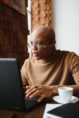 Kulaklık takan, kulaklık takan, Webinar eğitimi alan bilgisayar üzerinde öğrenim gören siyahi bir erkek öğrenci internette bilgi yazan dizüstü bilgisayarına bakıyor.