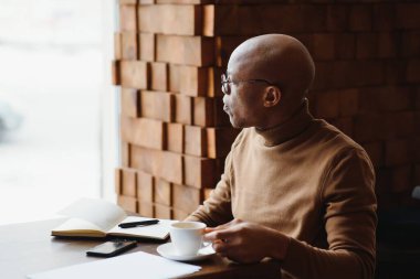 Günü planlıyorum. Sakin siyah öğrenci ders programını deftere yazıyor, modern barda oturuyor, boş bir yerde.