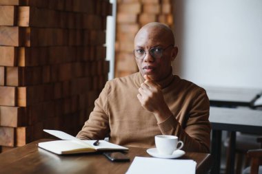 Günü planlıyorum. Sakin siyah öğrenci ders programını deftere yazıyor, modern barda oturuyor, boş bir yerde.