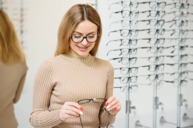 Görme ve görme duyusu - genç iş kadını optik mağazasında gözlük seçiyor