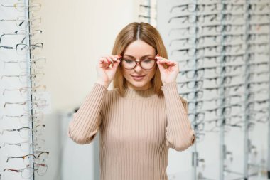 Görme ve görme duyusu - genç iş kadını optik mağazasında gözlük seçiyor
