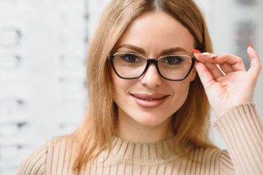 Güzel genç bayan optik mağazasından yeni gözlük seçiyor.