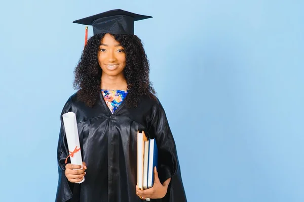Young African-American student in bachelor robe on color background