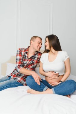 Kocası kanepede olan hamile bir kadın.