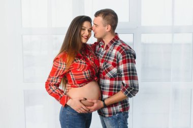 Sevgi dolu bir adam, hamile karısına arkadan sarılıyor. Evinin penceresinin yanında duruyor, boşluğu kopyalıyor.