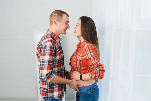 Milující Muž Objímající Svou Těhotnou Ženu Zezadu Stojící Okna Doma — Stock fotografie