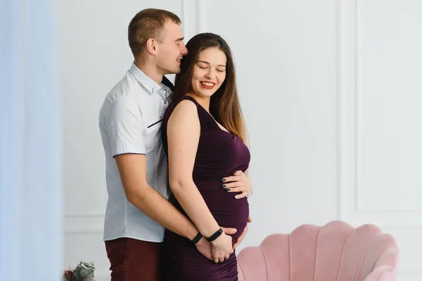 Amare Uomo Abbracciare Moglie Incinta Dietro Piedi Vicino Alla Finestra — Foto Stock