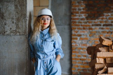 İnşaat konsepti. İnşaat alanında çalışan iş tulumu ve kasklı güzel bir kadın müteahhit..
