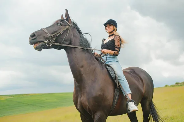 緑の畑で馬に乗っている若い女性 — ストック写真