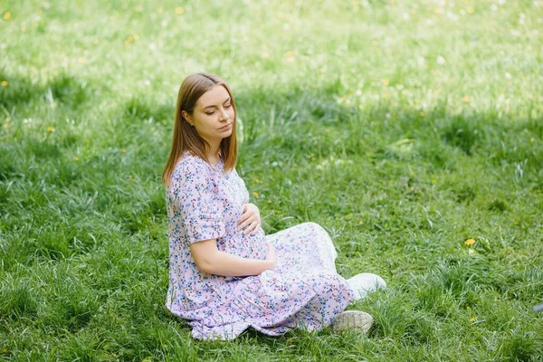 妊娠中の女性が公園で休んでいる — ストック写真