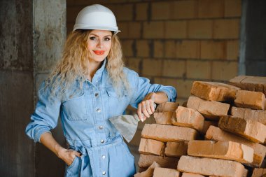 İnşaat mühendisi. İnşaat belgeleri olan bir kız. Binanın çatısına dayanmış beyaz şapkalı bir kadın. Yeni bir evin inşaatı.