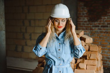 İnşaat mühendisi. İnşaat belgeleri olan bir kız. Binanın çatısına dayanmış beyaz şapkalı bir kadın. Yeni bir evin inşaatı.