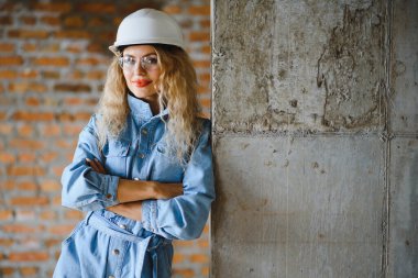 İnşaat mühendisi. İnşaat belgeleri olan bir kız. Binanın çatısına dayanmış beyaz şapkalı bir kadın. Yeni bir evin inşaatı.