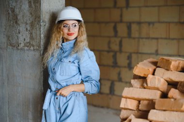 İnşaat mühendisi. İnşaat belgeleri olan bir kız. Binanın çatısına dayanmış beyaz şapkalı bir kadın. Yeni bir evin inşaatı.