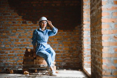 İnşaat konsepti. İnşaat alanında çalışan iş tulumu ve kasklı güzel bir kadın müteahhit..