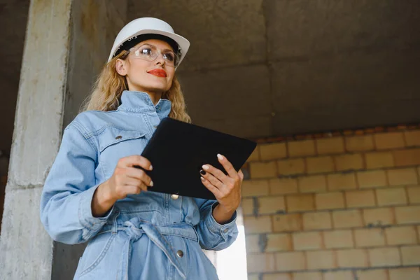 Warehouse woman worker. Woman builder in hardhat. Girl engineer or architect. Home renovation. Quality inspector. Construction job occupation. Construction worker. Lady at construction site.