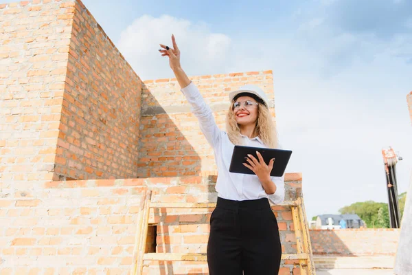 Female construction engineer. Architect with a tablet computer at a construction site. Young Woman looking, building site place on background. Construction concept