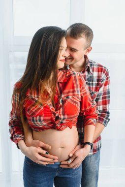 Sevgi dolu bir adam, hamile karısına arkadan sarılıyor. Evinin penceresinin yanında duruyor, boşluğu kopyalıyor.