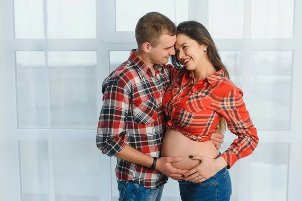 Milující Muž Objímající Svou Těhotnou Ženu Zezadu Stojící Okna Doma — Stock fotografie