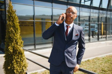 Afrikalı yöneticinin portresi cep telefonuyla yürüyor ve konuşuyor.