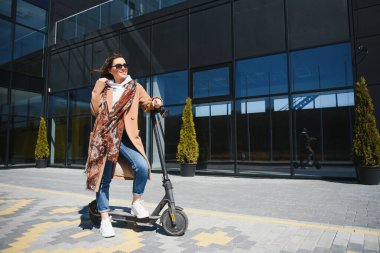 İşe elektrikli scooterla giden genç, güzel bir kadın, modern kız, yeni nesil, elektrik nakli, ekolojik ulaşım, ekolojik ulaşım, gün batımı