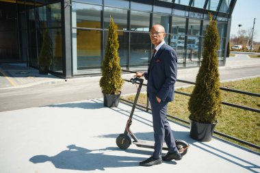 Mobiletli bir iş adamı modern iş binasının önünde telefonla konuşuyor..