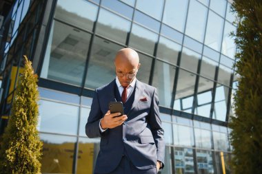 Afrikalı yöneticinin portresi cep telefonuyla yürüyor ve konuşuyor.