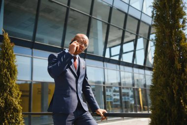 Genç bir Afro-Amerikan iş adamının portresi. Şehirdeyken cep telefonuyla konuşuyor.