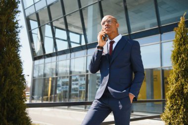 Afrikalı yöneticinin portresi cep telefonuyla yürüyor ve konuşuyor.