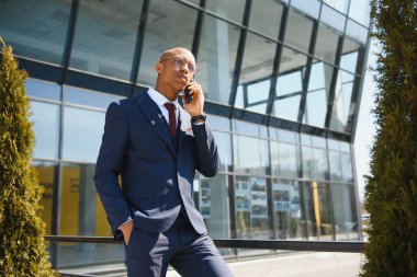 Afrikalı yöneticinin portresi cep telefonuyla yürüyor ve konuşuyor.