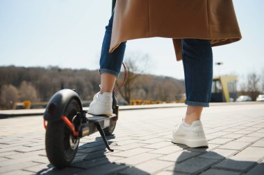 Şehir manzarasında, hareket bulanıklığında siyah elektrikli scooter kullanan bir kadın.