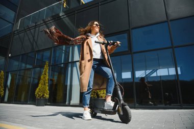 İşe elektrikli scooterla giden genç, güzel bir kadın, modern kız, yeni nesil, elektrik nakli, ekolojik ulaşım, ekolojik ulaşım, günbatımı, elektrikli kaykay.