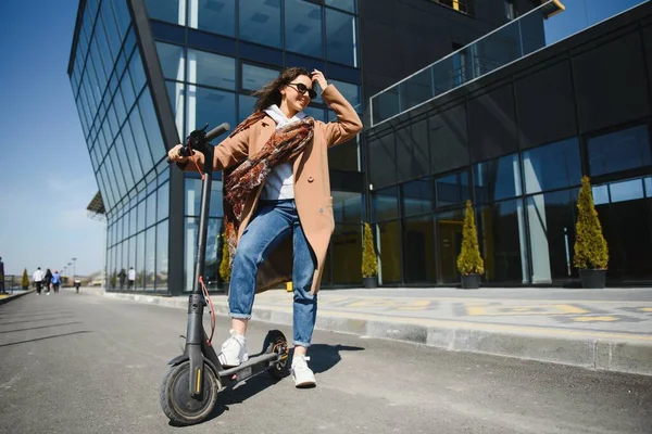 Junge Frau Auf Dem Elektroroller Vor Dem Hintergrund Eines Bürogebäudes — Stockfoto